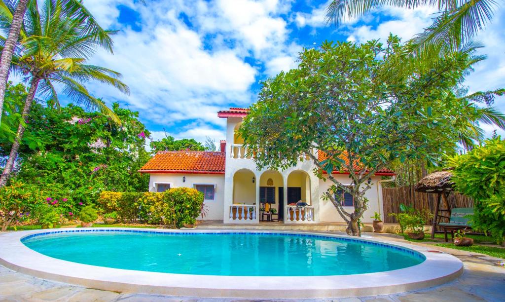 a villa with a swimming pool in front of a house at Banana House Villas in Watamu