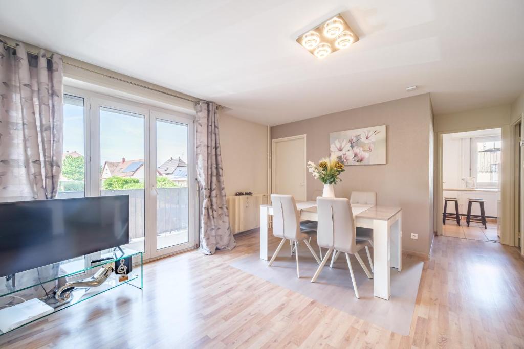 - un salon avec une table à manger et une grande fenêtre dans l'établissement La Symphonie - Joli appt à Colmar, à Colmar