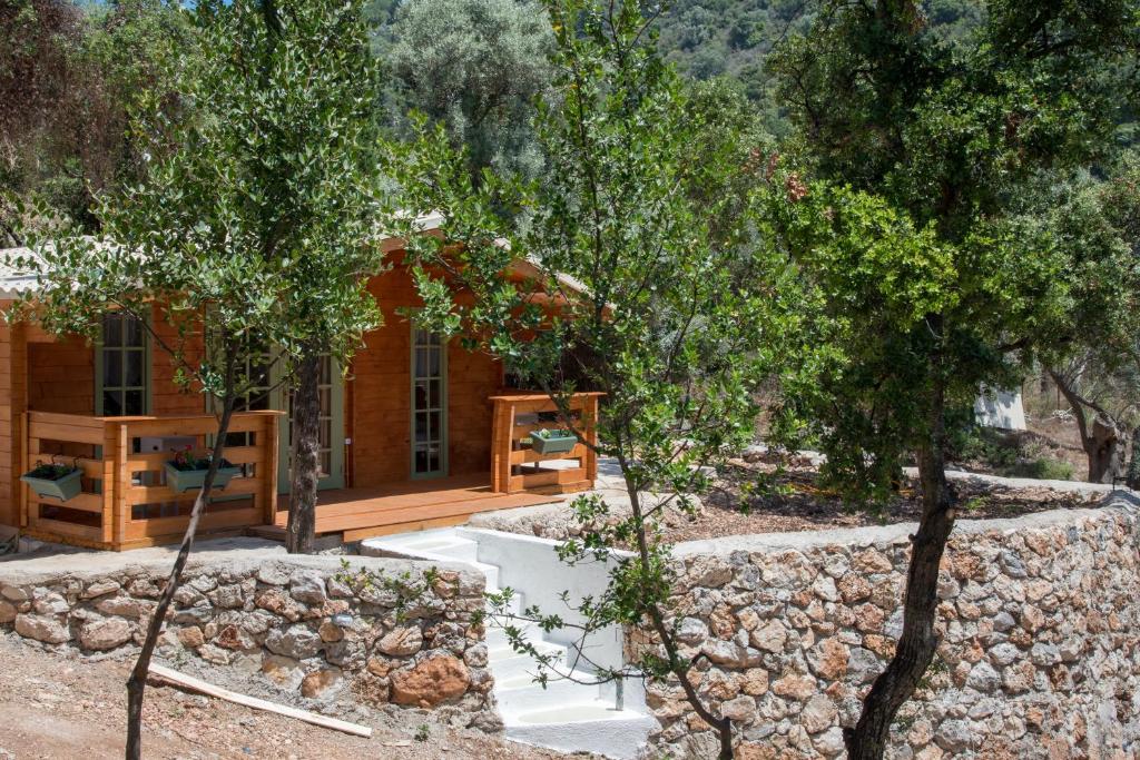eine Blockhütte mit einer Steinmauer und Bäumen in der Unterkunft metaxaki cottage in Mikros Gialos