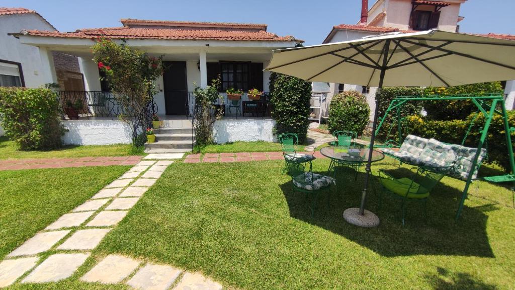 a patio with a table and an umbrella in a yard at Agios Mamas beach house in Áyios Mámas