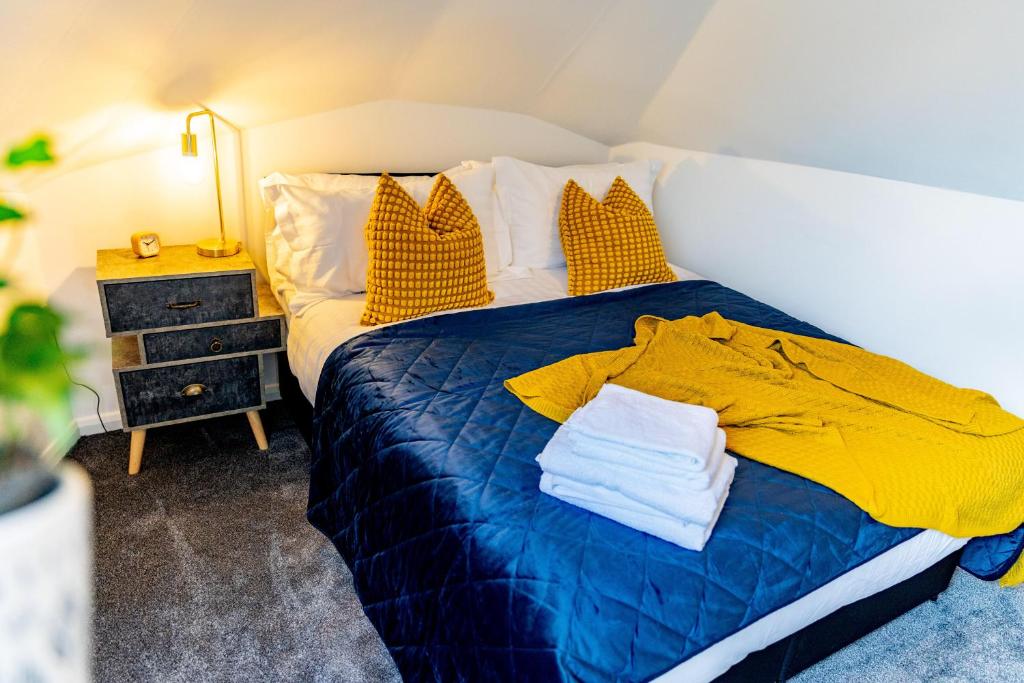 a bed with a blue blanket and yellow pillows at Cosy flat with Modern Luxuries in Sheffield