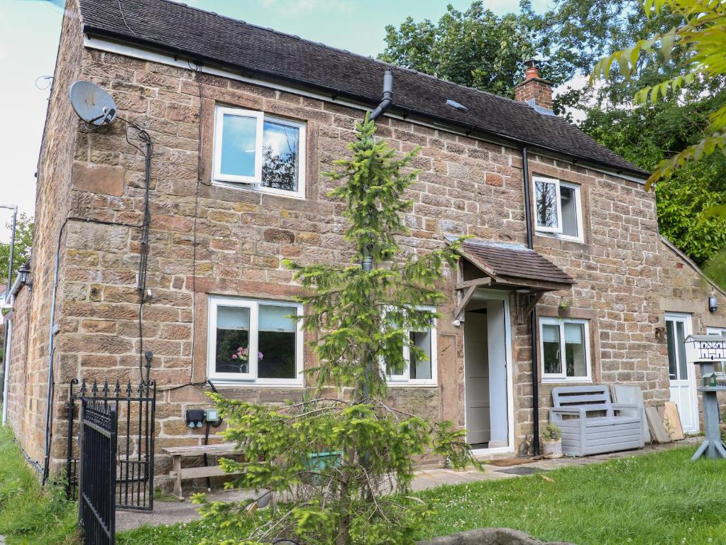 a brick house with white windows and a gate at Midway Cottage in Matlock