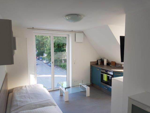 Zimmer mit einem Bett und einer Küche mit einem Fenster in der Unterkunft hochwertiges Studio in bester Lage in Friedrichshafen