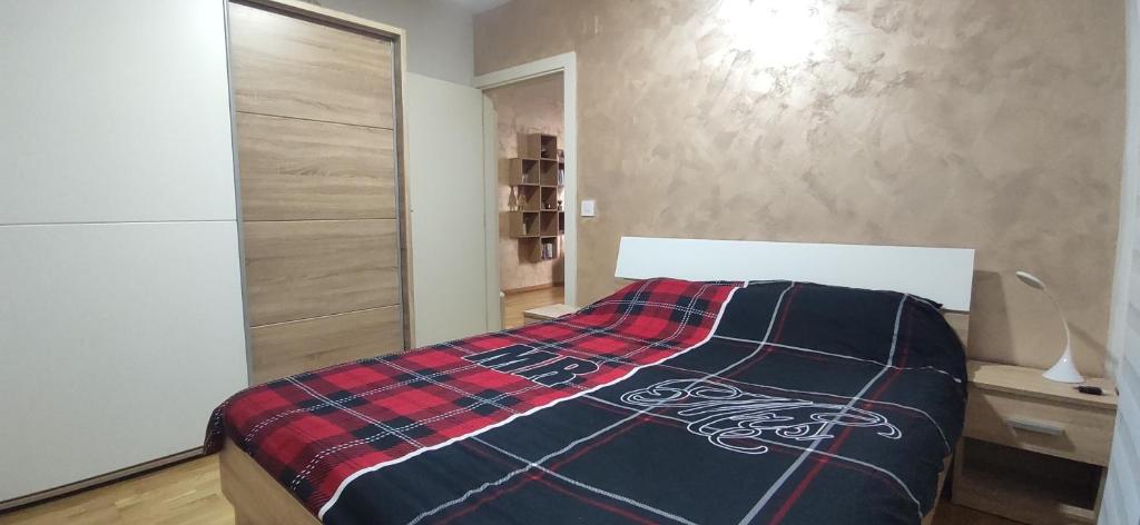 a bedroom with a bed with a plaid blanket on it at Lui Apartment in Novi Grad