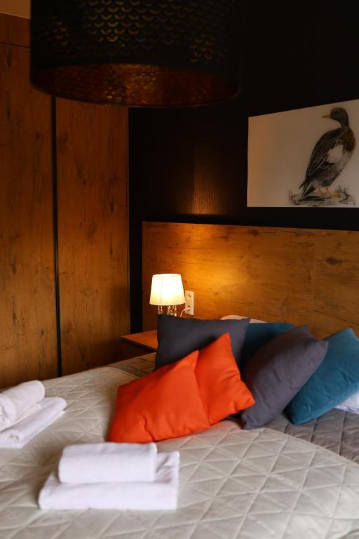 - un lit avec des oreillers orange et bleu et une lampe dans l'établissement Keller Apart K12 - Taras z widokiem na wyłączność i klimatyzacją GRATIS, à Porąbka