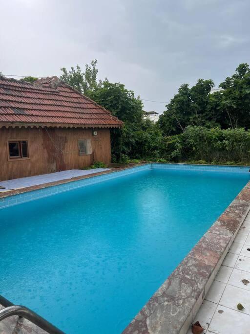 a large blue swimming pool next to a house at Havuzlu ahşap ev in Gemlik