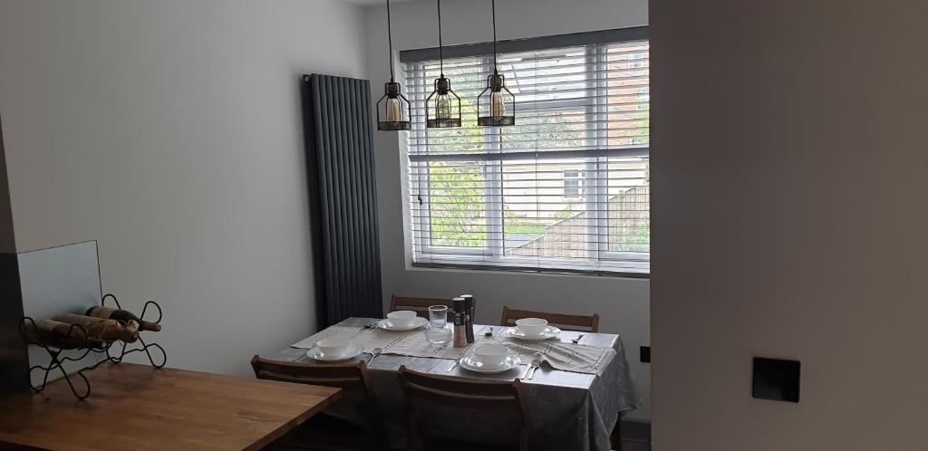 ein Esszimmer mit einem Tisch und einem Fenster in der Unterkunft Three Kings Luxe Escape in London