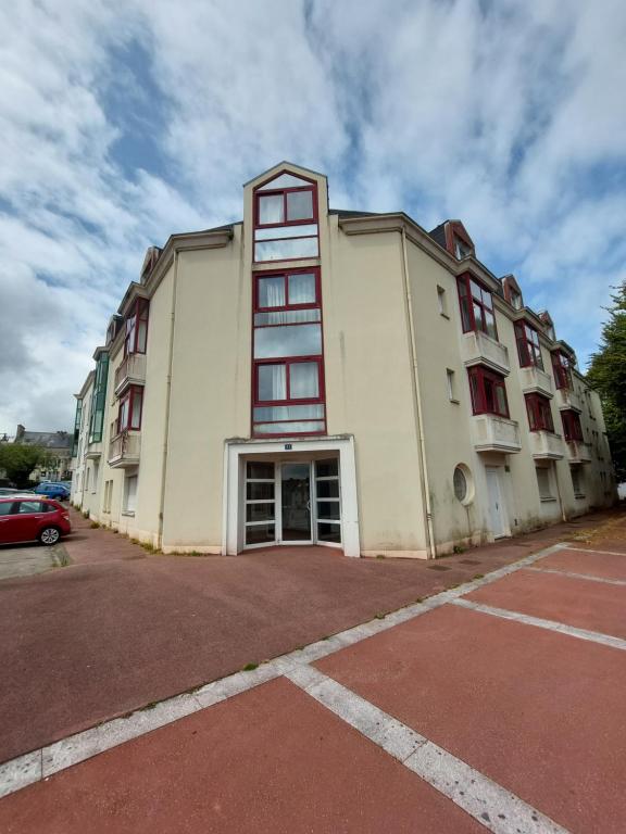 a large white building with red windows and a parking lot at Le Studio Zen "parking gratuit" in Cherbourg en Cotentin