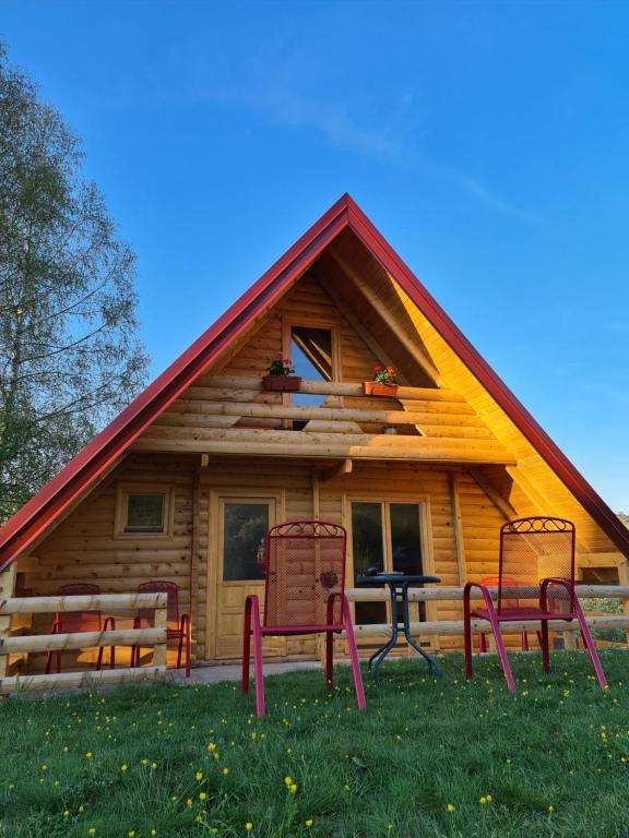 uma cabana de madeira com três cadeiras à frente em Nika em Nova Varos