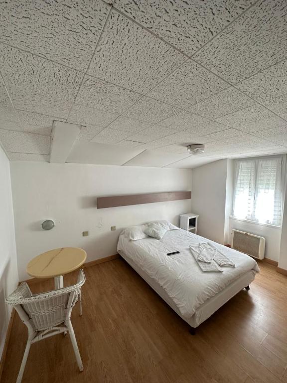 1 dormitorio con cama, mesa y techo en Hôtel de Nantes, en La Bernerie-en-Retz