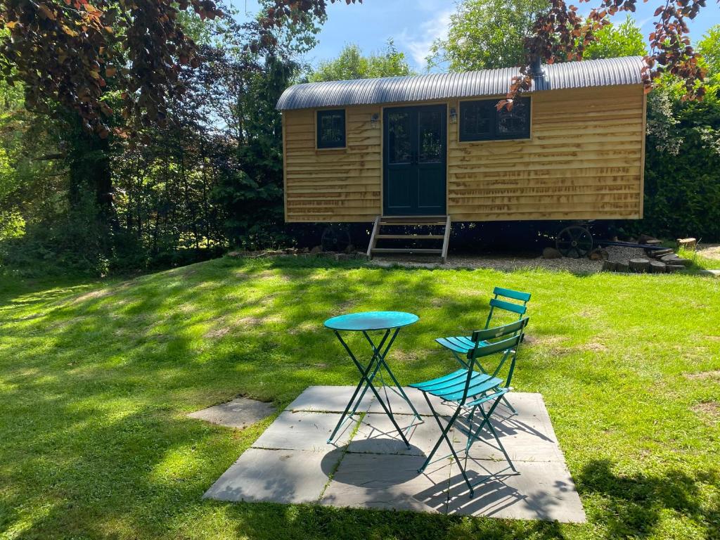 um par de cadeiras e uma mesa em frente a uma cabana em Lingfield Shepherds Hut em Blindley Heath