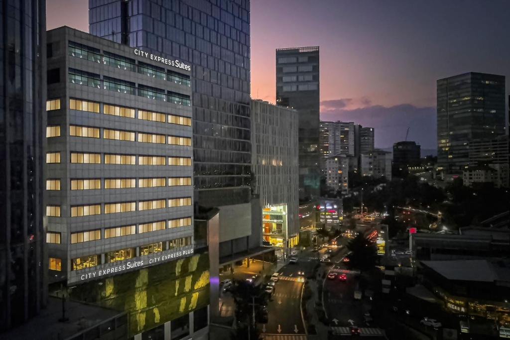 - une vue sur une ville de nuit avec des bâtiments dans l'établissement City Express Plus by Marriott Santa Fe, à Mexico