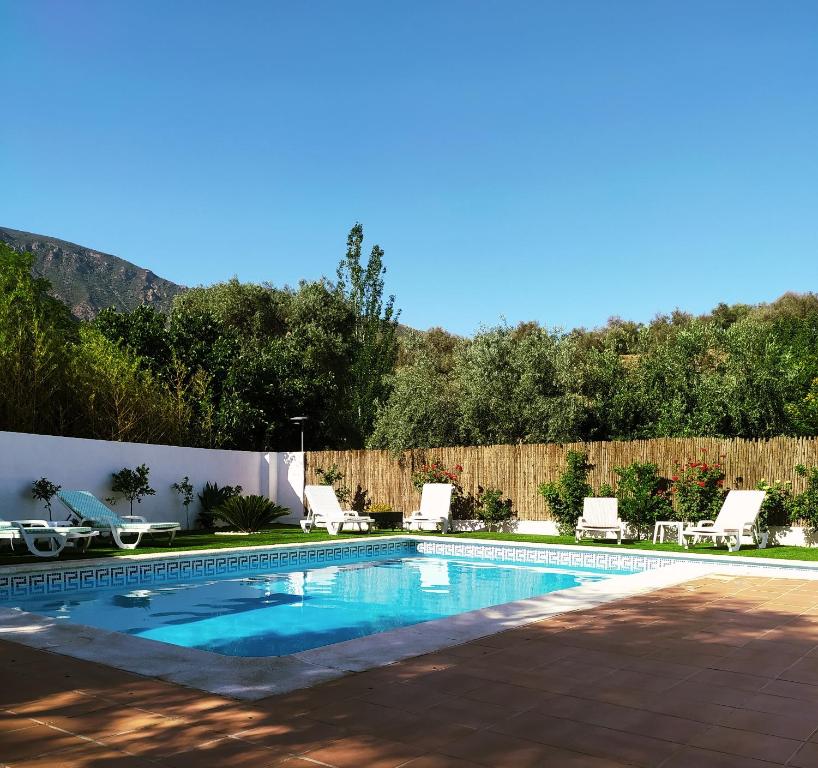 una piscina en un patio con sillas y una valla en CORTIJO LALO, en Órgiva