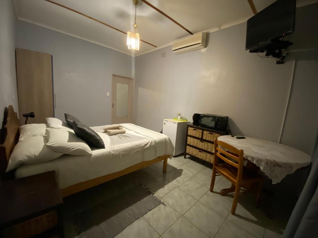 促美布的住宿－El-Kole Bed and Breakfast，一间卧室配有一张床、一张书桌和一台电视