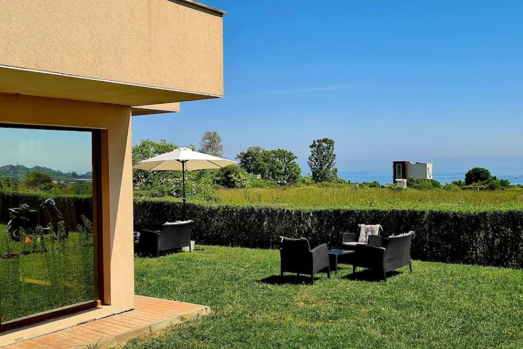 a patio with chairs and an umbrella in the grass at Seagarden Villa Resort / Villa Dimar 2 in Lozenets