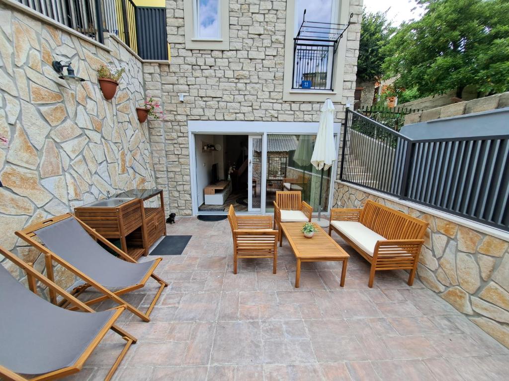 a patio with chairs and tables and a stone wall at Vila Kamicić in Baška