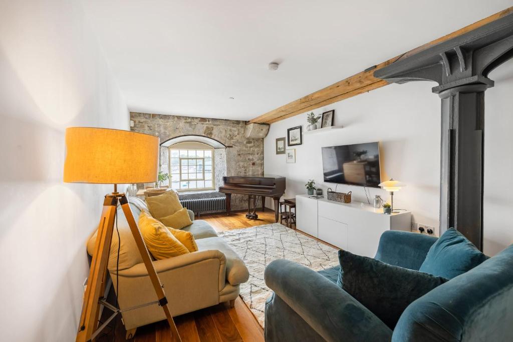 a living room with blue couches and a piano at Luxury 2 bed Apartment in historic Royal William Yard in Plymouth