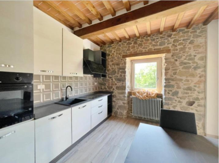 a kitchen with white cabinets and a stone wall at Casa vacanze Raggio di Sole in Grotte