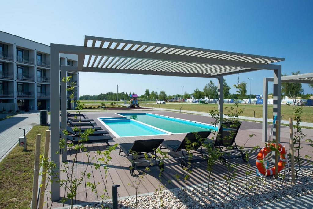 a swimming pool under a pergola next to a building at Nauji apartamentai su šildomu baseinu, sporto sale, vaikų kambariu, work zona in Palanga