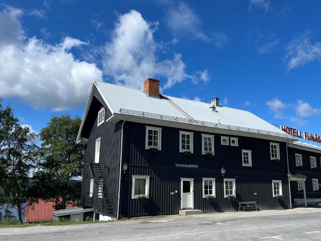 a black house with a white roof on a street at Vandrarhem Funäsdalen in Funäsdalen