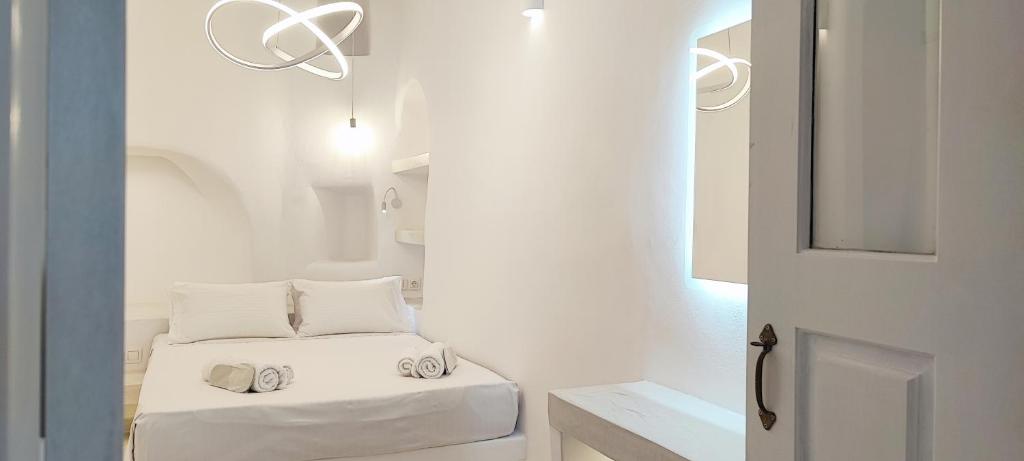 a white room with a bed with white pillows at Cozy Now in Tinos