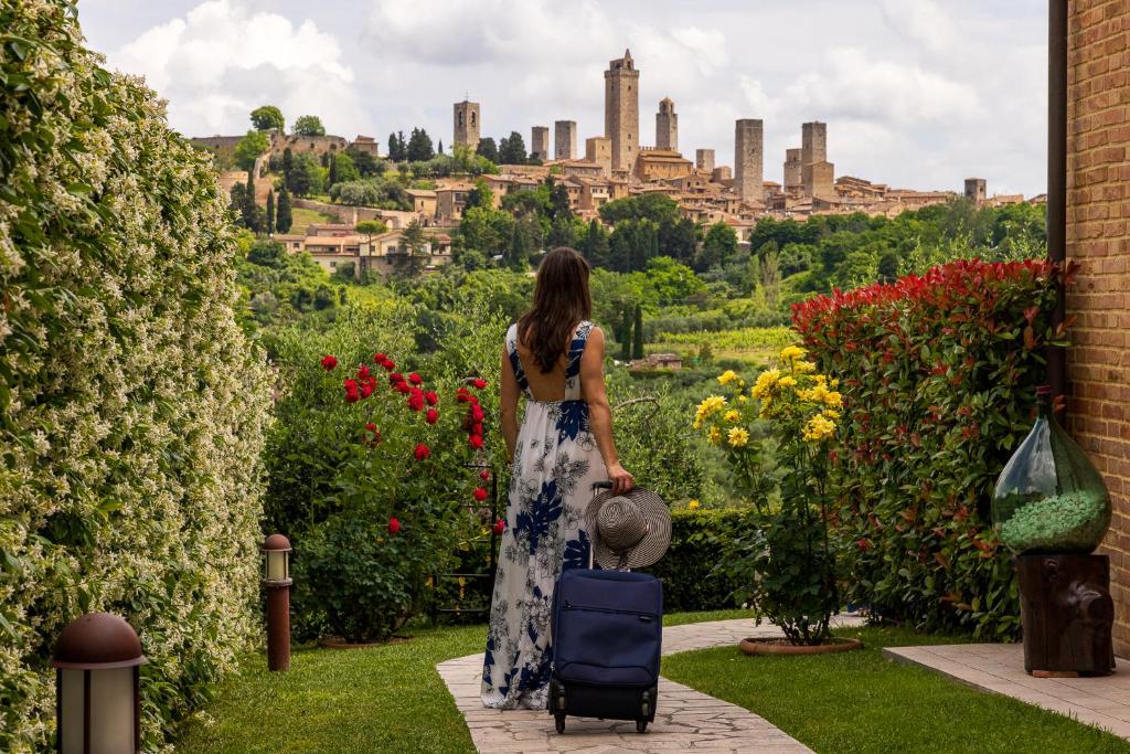 uma mulher com uma mala a olhar para uma cidade em B&B La Cornice em San Gimignano