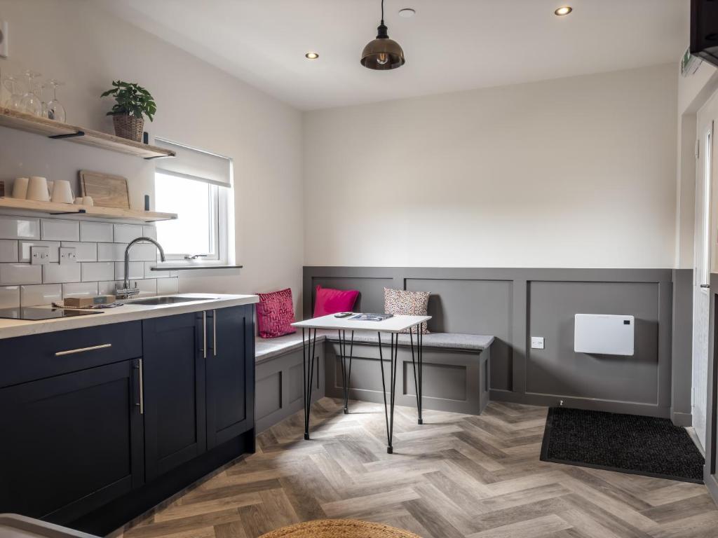 a kitchen with black cabinets and a sink and a table at Goodstay Lodges by Urban Space in Barry