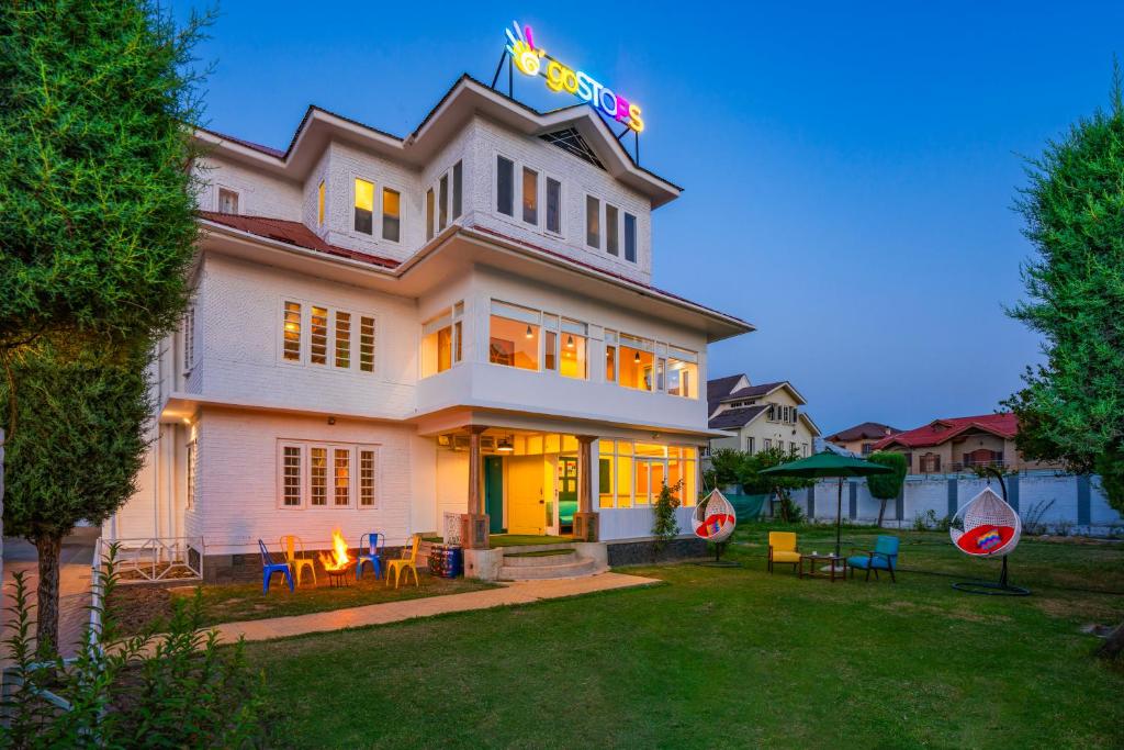 duży biały dom ze stołami i krzesłami na dziedzińcu w obiekcie goSTOPS Srinagar w mieście Śrinagar