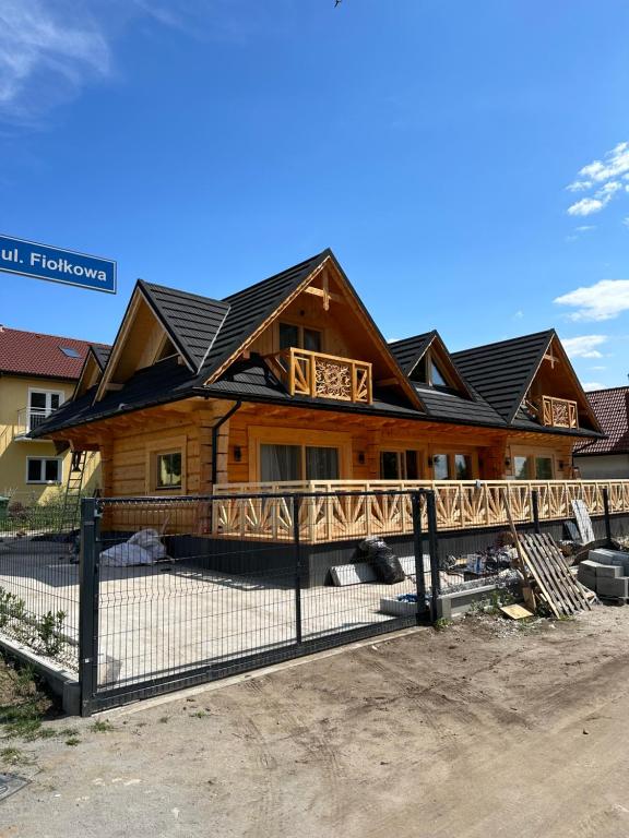 a log home with a fence in front of it at Roomflacja Bałtyk in Sianozety