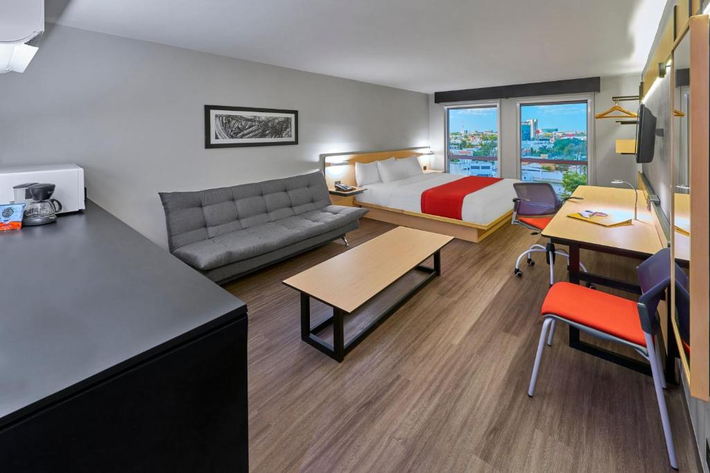 a hotel room with a bed and a couch at City Express by Marriott Mérida in Mérida