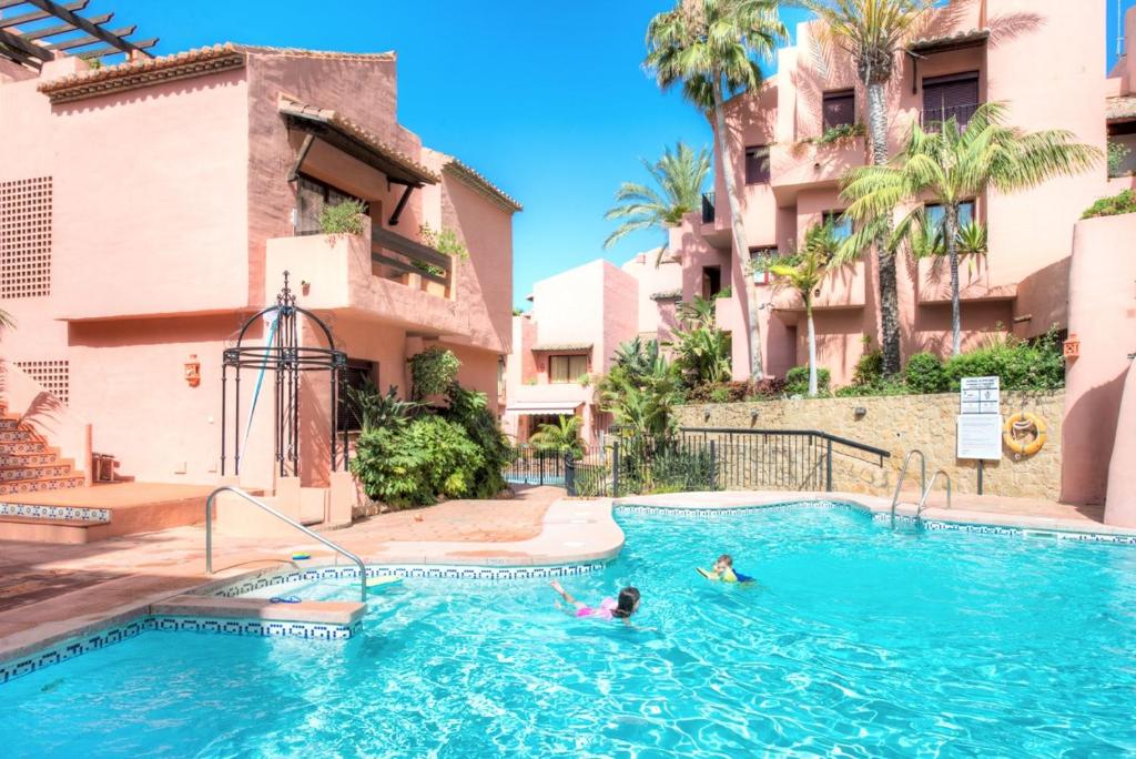 Luxury penthouse in Jardines de Don Carlos في مربلة: شخصين يسبحون في مسبح في فندق