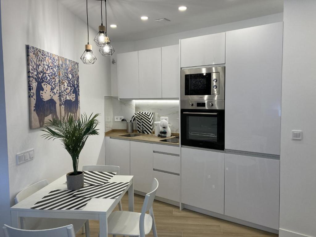 una cocina con armarios blancos y una mesa con una maceta. en Bravo Murillo Apartments, en Madrid