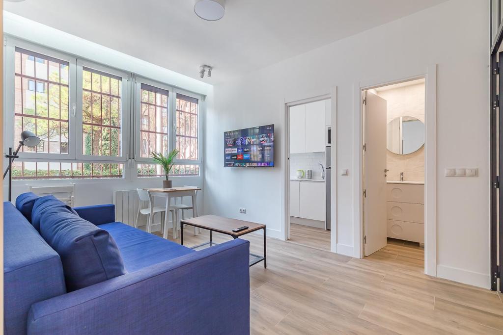 ein Wohnzimmer mit einem blauen Sofa und einem Tisch in der Unterkunft Arturo Soria Apartments3 in Madrid