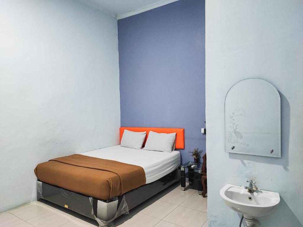 a bedroom with a bed with an orange headboard and a sink at Reddoorz @ Hotel Bersaudara Bungo in Muarabungo