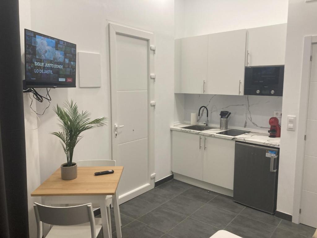 una cocina con armarios blancos y una mesa con una maceta. en Ensanche1 Apartments en Madrid