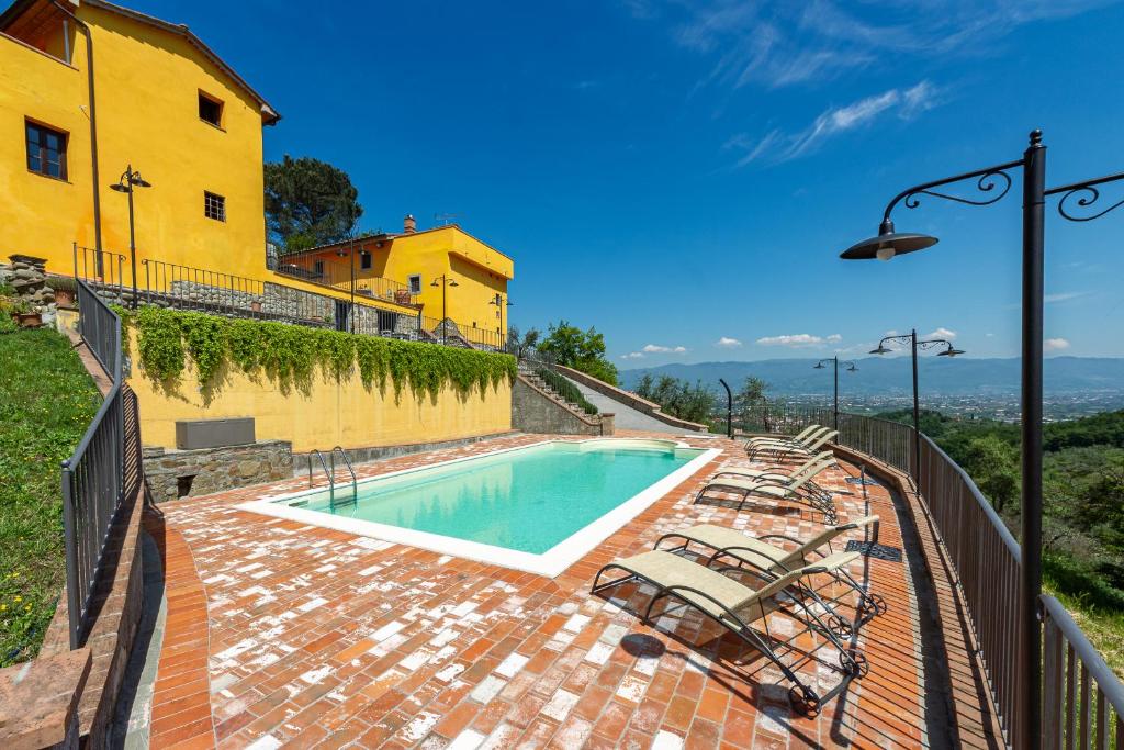 una piscina frente a un edificio amarillo en Casale della Visitazione by VacaVilla, en Cantagrillo