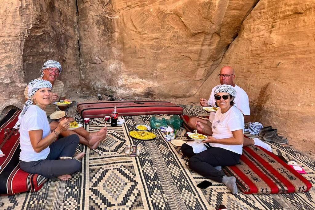 a group of people sitting on a bed eating food at The White Bedouin in Wadi Rum