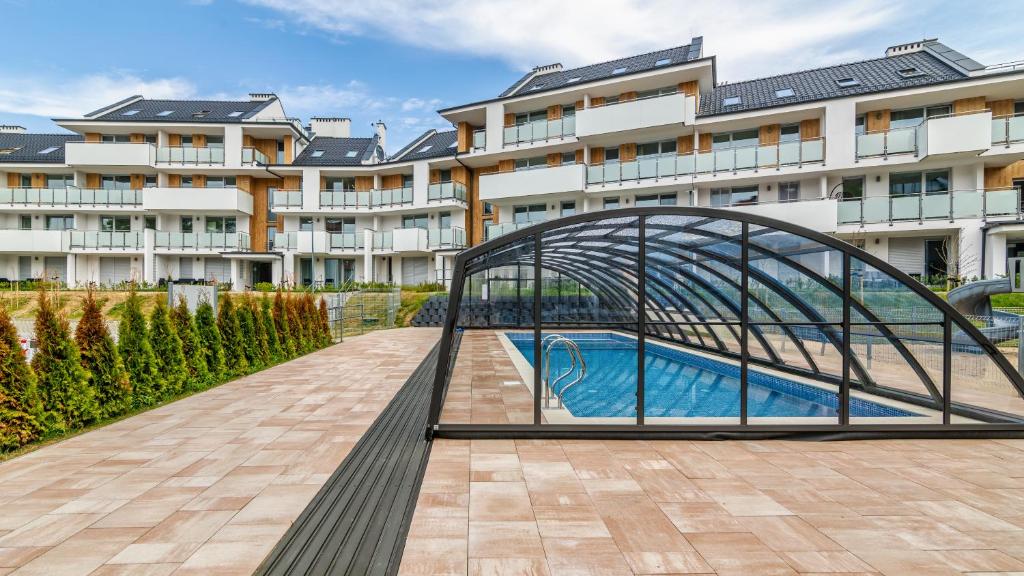 a metal bridge over a swimming pool in front of a building at Baltic Garden Sztutowo Apartamenty PIAMOLA in Sztutowo
