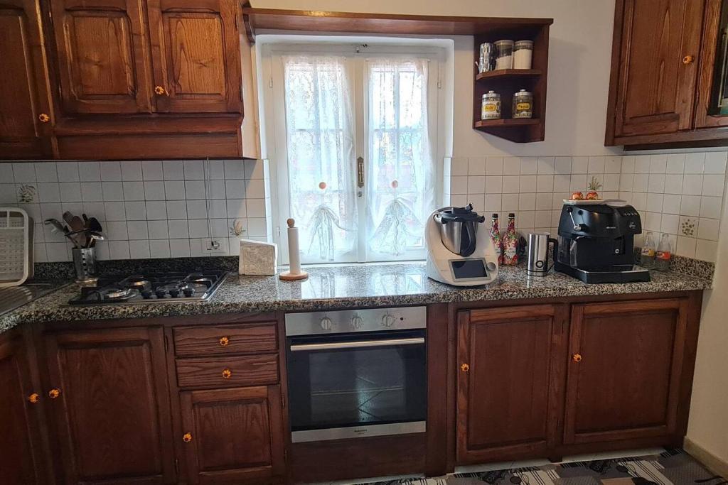 uma cozinha com armários de madeira, um fogão e uma janela em CASA VACANZA DA ROSI em Carrara