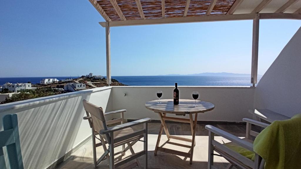 una mesa con 2 sillas y una botella de vino en el balcón en Aegean Dream Apartments, en Tinos