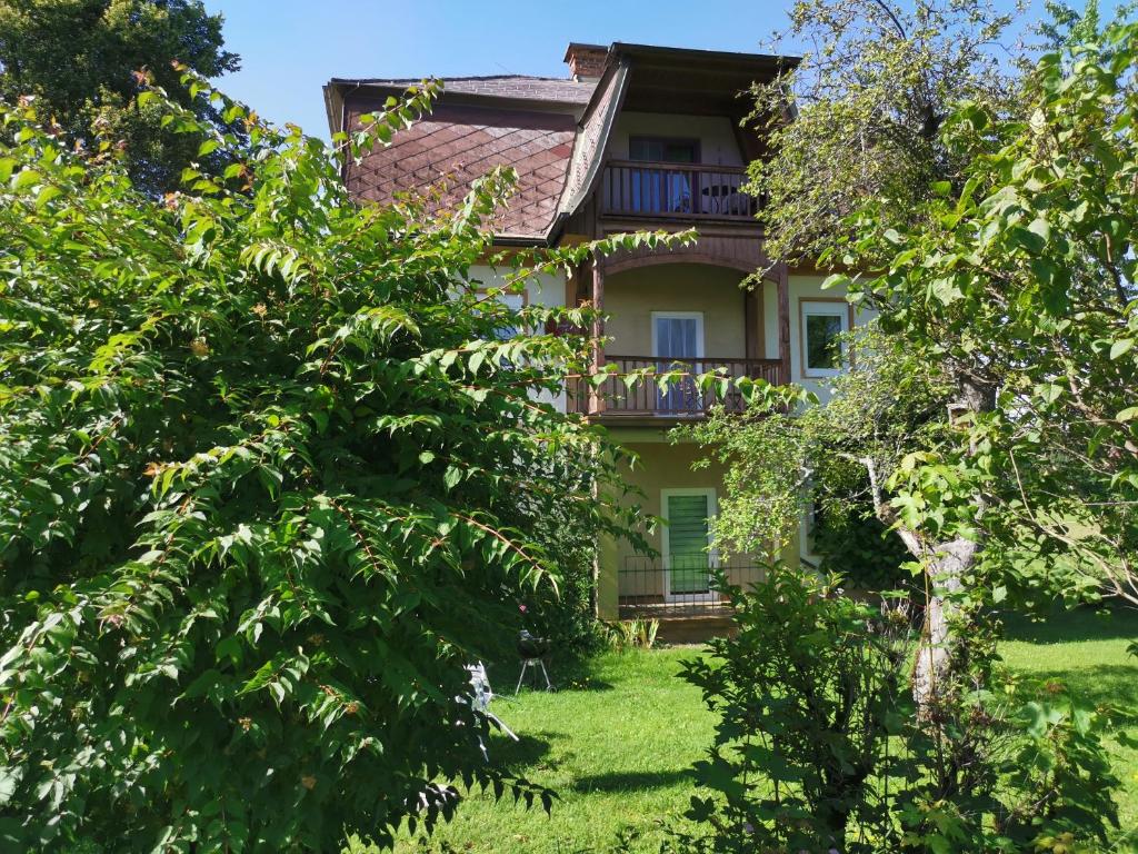 ein altes Haus mit Bäumen davor in der Unterkunft Bungalow & Apartments "Am Deber" Velden - Augsdorf in Velden am Wörthersee