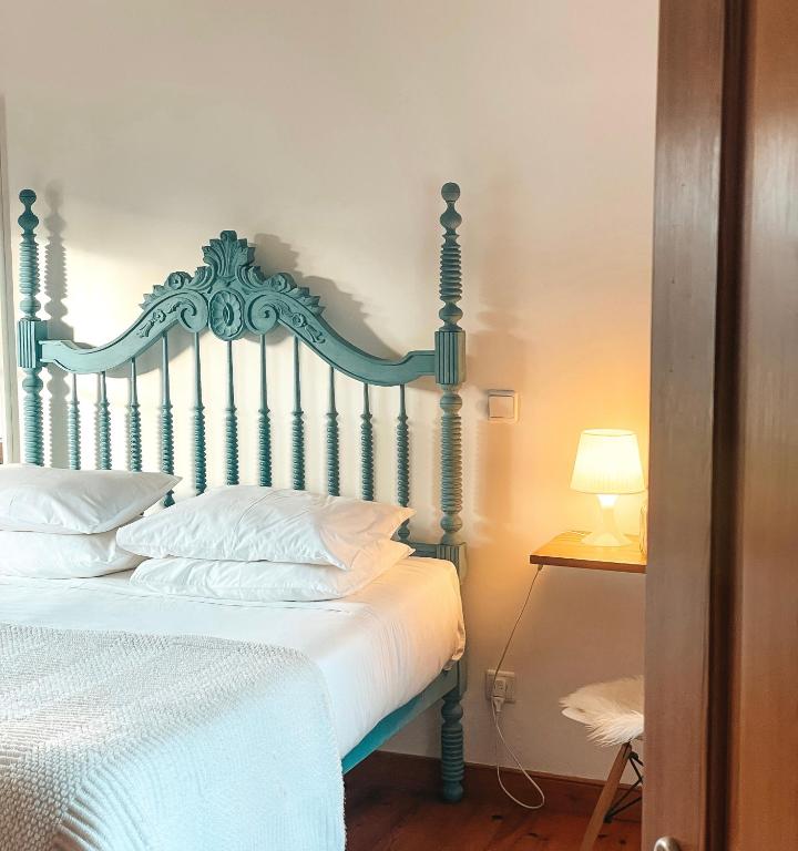 a bedroom with a bed with white sheets and a lamp at Quinta Amarela - B&B in Nazaré