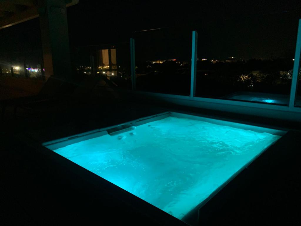 a jacuzzi tub in a room with a window at night at Suite Luxury Seaview in Misano Adriatico