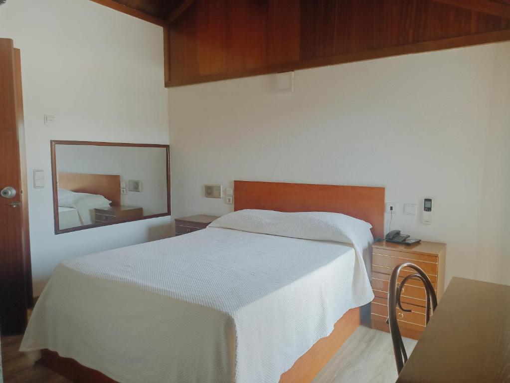 a bedroom with a white bed and a mirror at Residencial Dona Teresa in Maia