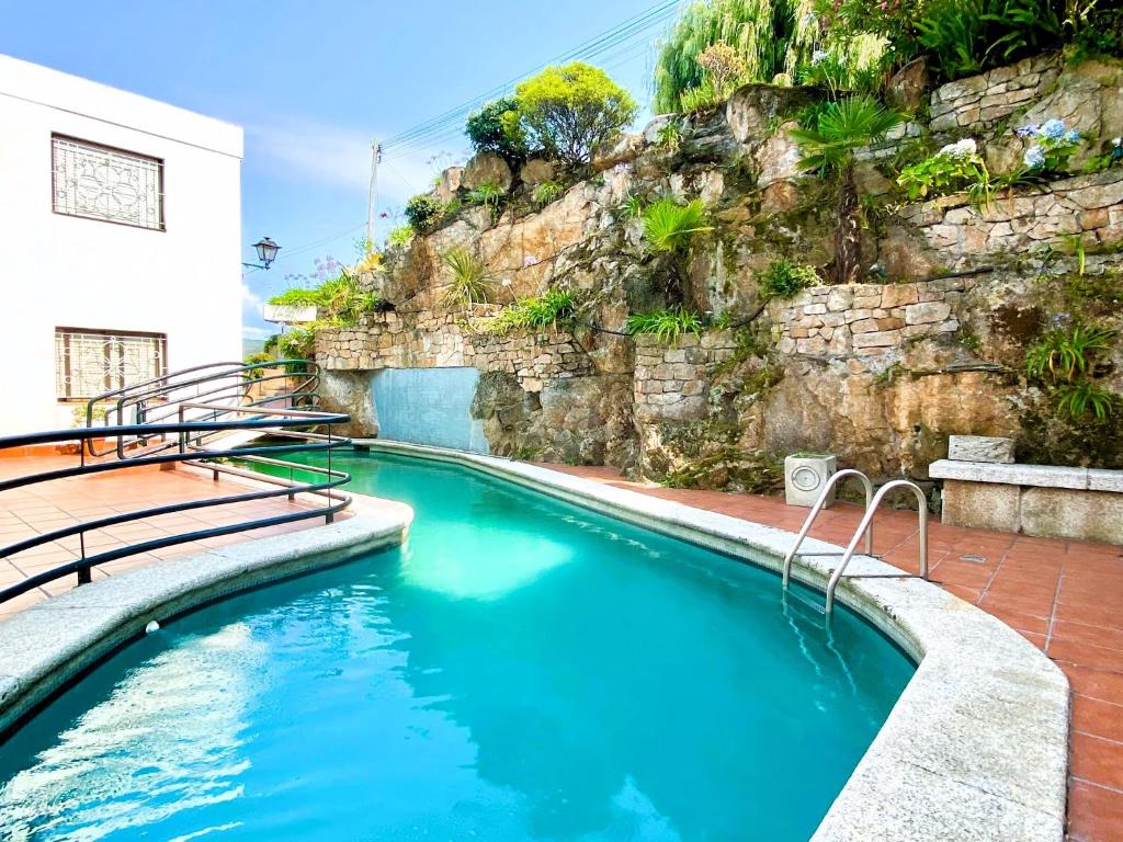 a swimming pool with blue water and a stone wall at Apartamento Playa Calzoa in Vigo