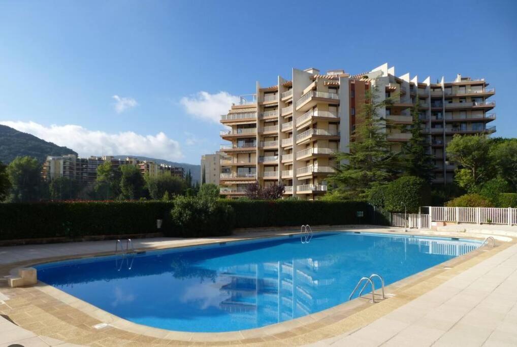 a large swimming pool in front of a tall building at 2 Pièces Piscine Parking Clim - Le Fairway in Mandelieu-La Napoule