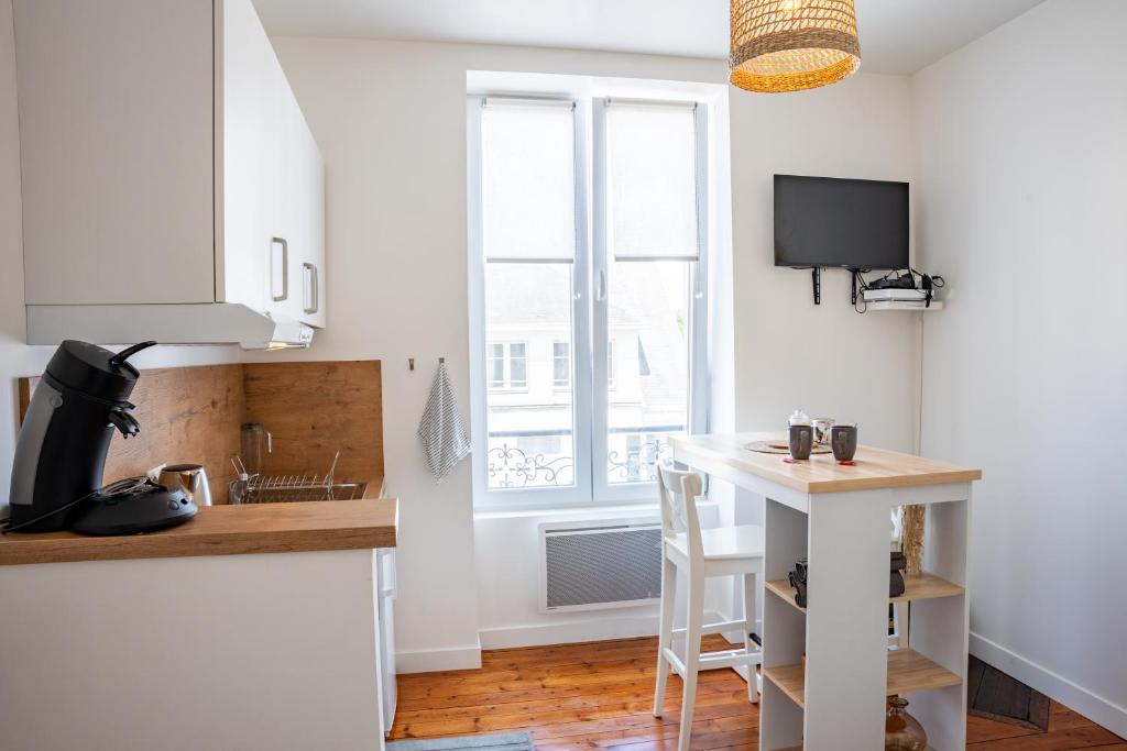 a kitchen with white cabinets and a table and a window at La Mésange Huppée #8 Gare in Quimper