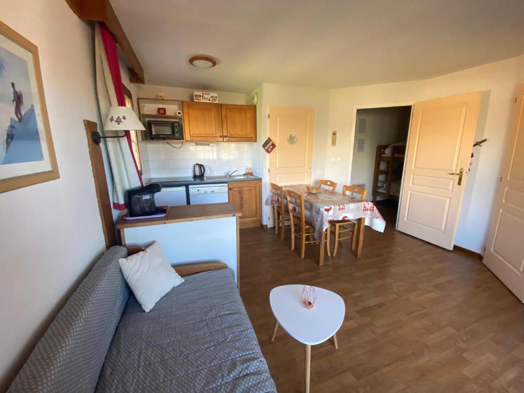 ein Wohnzimmer und eine Küche mit einem Sofa und einem Tisch in der Unterkunft La Crete du Berger by Actisource, La Joue du Loup in La Joue du Loup