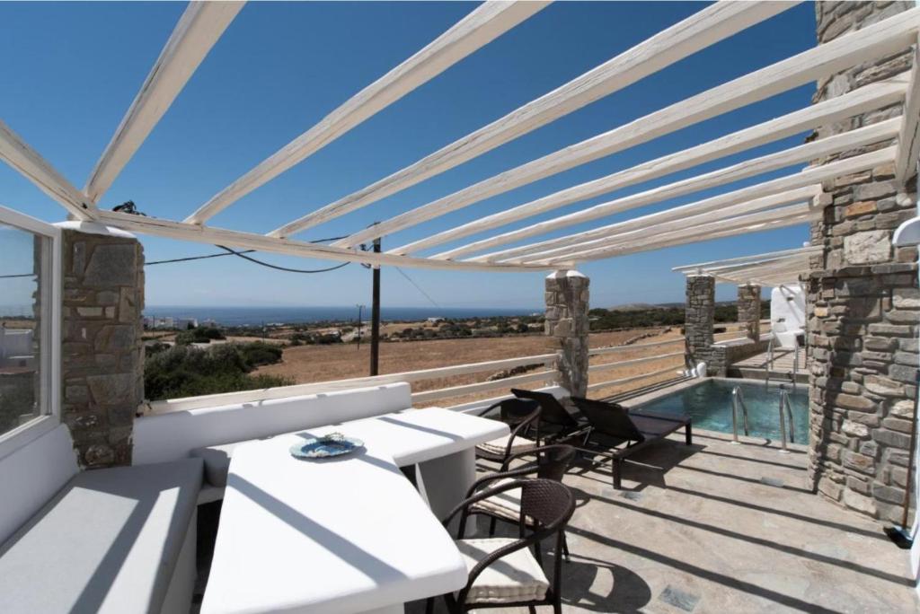 een patio met een tafel en stoelen en een zwembad bij Villa Aspro Paros 1 in Drios