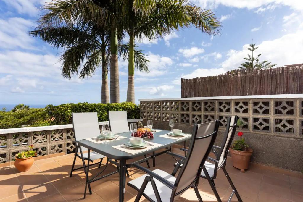 a table and chairs on a patio with palm trees at Casa Carolina in Puntillo del Sol